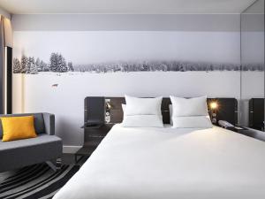 a bedroom with a large bed and a chair at Novotel London Waterloo in London +101 photos
