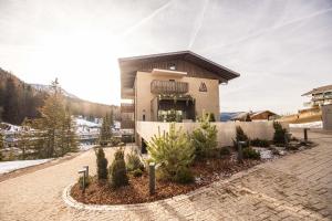 a house in the middle of a courtyard with trees at Alma Alpina Lodge, Adults Only in Obereggen