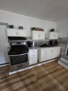 a kitchen with a stove and white cabinets at The Cottage in Dagsboro +8 photos