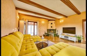 a living room with a yellow couch and a tv at Wellness Villa close to Prague in Kuchař