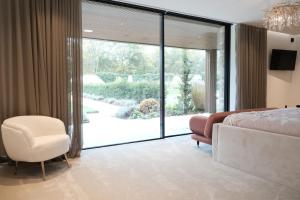 a bedroom with a bed and a chair and a sliding glass door at The Walled Garden House Rooms Only Not Entire House in Mundford