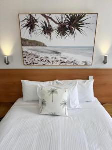 a bedroom with a white bed with palm trees above it at Nambour Heights Motel in Nambour