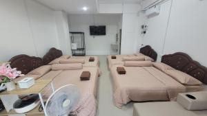 a room with two beds and a table with a fan at beMyGuest Bangsaen in Ban Thai Don (1)