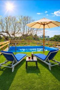 zwei Stühle und ein Sonnenschirm neben einem Pool in der Unterkunft Casita Bonita in Villafamés