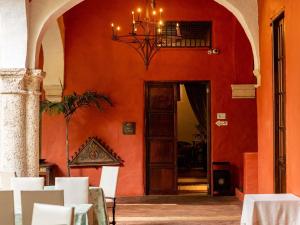 a dining room with an orange wall and a chandelier at Sofitel Legend Santa Clara Cartagena in Cartagena de Indias +270 photos