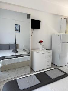 a white bedroom with a bed and a refrigerator at Jenny's Holiday Villas in Polychrono
