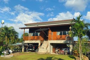 a house with a balcony on the side of it at หินผาปัว รีทรีต & หินผาโฮมสเตย์ in Ban Choko