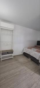 a white bedroom with a bed and a wooden floor at Cherry Garden Apartment in Podgorica
