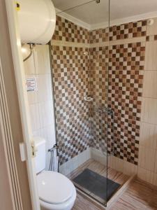 a bathroom with a toilet and a glass shower at Harmony beach house in Roda
