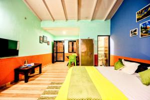 a room with a bed and a desk and a television at Aasara Homestay Bhimtal Orchard Villa in Bhīm Tāl
