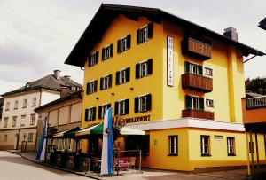 żółty budynek z czarnym dachem w obiekcie Hotel Gasthof Tirolerwirt w mieście Bischofshofen