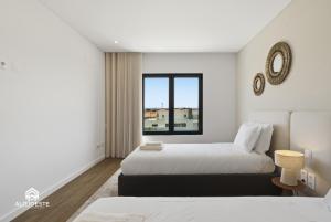 a white bedroom with two beds and a window at Ondas do Oeste - 3 bedroom villa in Silveira