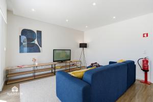 a living room with a blue couch and a television at Ondas do Oeste - 3 bedroom villa in Silveira