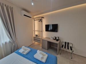 a bedroom with a bed and a desk with a television at Acqua Marina Rooms in La Caletta