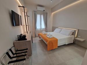 a bedroom with a bed and a table and a television at Acqua Marina Rooms in La Caletta