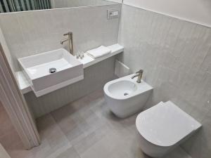 a white bathroom with a toilet and a sink at Acqua Marina Rooms in La Caletta +13 photos