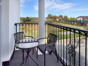 two chairs and a table on a balcony with a view at Rezydencja De Rosse in Jastrzębia Góra