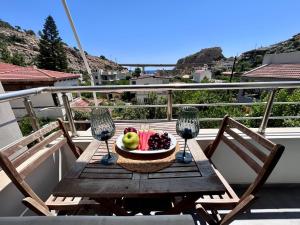 a table with a bowl of fruit and two wine glasses at elva creta beach in Palaiokastro