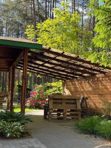 a wooden bench under a wooden pergola at Chata przy lesie - sauna i balia in Łuka