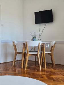 a dining room table and chairs with a tv on a wall at Apartmani Zinda in Sukošan