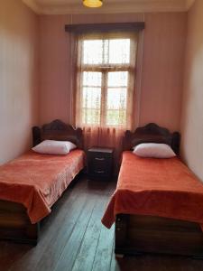 a bedroom with two beds and a window and wooden floors at Motena Guesthouse in Martvili