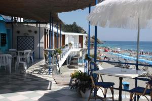 a patio with tables and chairs and the beach at Hotel Bagni Arcobaleno in Deiva Marina