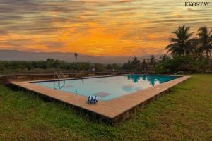 a swimming pool with a sunset in the background at EKOSTAY - Utopian Villa with Jacuzzi in Candolim