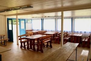 a room with wooden tables and benches and windows at DrótSzarvas Üdülőház in Bogács