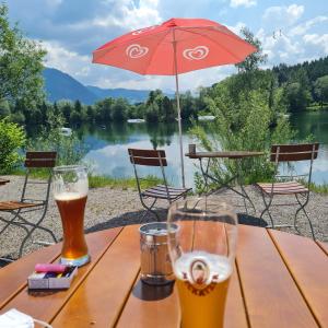 a wooden table with two glasses of beer and an umbrella at Grüntenausblick Erholung zwischen Alpenpanorama Seen und Wanderwegen in Rettenberg