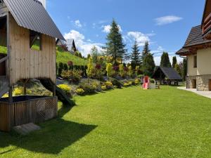 a yard with a house and a garden with flowers at Apartament u SKOCZKA in Poronin