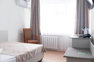 a bedroom with a bed and a desk and a window at Aktobe Hotel in Aktobe