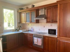 a kitchen with wooden cabinets and a stove top oven at La Perla Villa del Lago in Paloznak