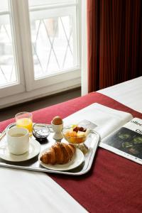 a breakfast tray with a plate of food on a bed at Hotel Choiseul Opera in Paris
