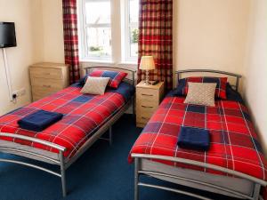 a bedroom with two beds with red and blue sheets at Morlich Guesthouse in Dingwall