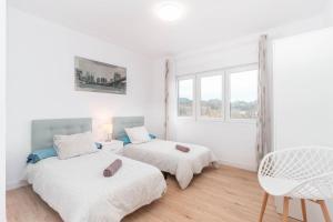 a white bedroom with two beds and a window at Apartamento La Salamandra in Arriondas