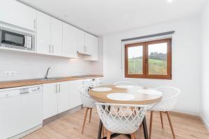 a kitchen with a wooden table and white cabinets at Apartamento La Salamandra in Arriondas +7 photos