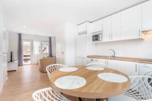 a kitchen with a wooden table and white cabinets at Apartamento La Salamandra in Arriondas