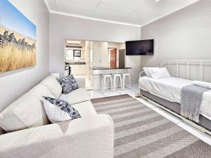 a white living room with a couch and a bed at Manzini Chalet no20 in St Lucia