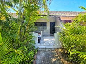 a house with palm trees in front of it at Manzini Chalet no20 in St Lucia