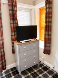 a television on a dresser in a room with a window at Morlich Guesthouse in Dingwall +25 photos
