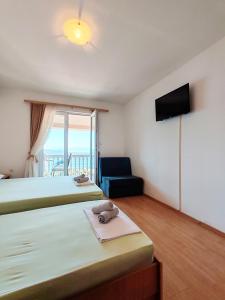 a bedroom with two beds and a television and a chair at Apartment & Rooms Tempera in Neum