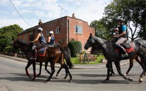 un grupo de personas montando caballos por la calle en Manor House Inn, en Ditcheat