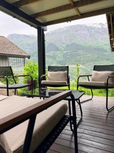 a deck with chairs and tables and a view of mountains at StarapApartment Odda 3 BR in Odda +7 photos