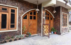 a stone building with wooden doors and potted plants at Quinton Enclave in Shillong