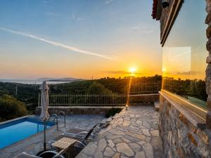a villa with a pool and a sunset at Villa Rokanes Glass Stone with Pool in Kouvéllai