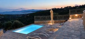 a swimming pool with chairs and a table and a sunset at Villa Rokanes Glass Stone with Pool in Kouvéllai