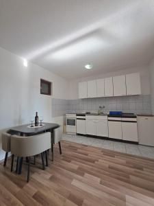 a kitchen with white cabinets and a table in a room at Apartment & Rooms Tempera in Neum