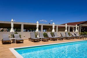 a pool with chairs and umbrellas next to a building at Hotel Akrothalassia J I K in Leptokarya