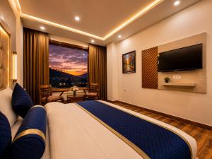 a bedroom with a large bed with a flat screen tv at Hotel Woods inn Dalhousie #MBS Travels # Rooftop # Restaurant # Top Rated Property in Dalhousie
