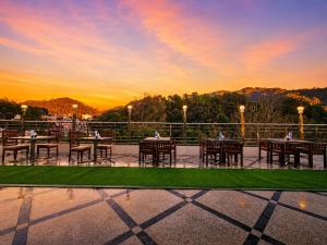 a patio with tables and chairs with a sunset in the background at Hotel Woods inn Dalhousie #MBS Travels # Rooftop # Restaurant # Top Rated Property in Dalhousie
